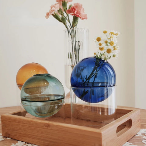 Collection of vases on a wooden tray with flowers