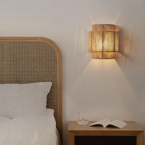 Woven wall light on wall next to bed and above bedside table
